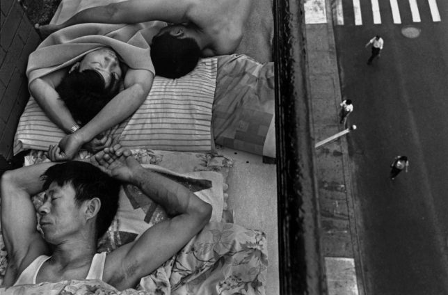 Black and white photograph, taken by the artist Chien-Chi Chang in New York, USA in 1998. This work shows us immigrants sleeping on the fire escape of a building to escape the heat wave.